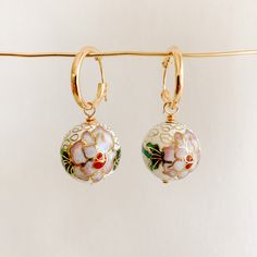 Add a unique touch to your look with our Floral Cloisonné Drop Hoop Earrings. These beautiful earrings feature rare cloisonné enamel beads, adding a playful pop of color to any outfit. Each pair is a wearable work of art, with subtle colors and removeable charms. A truly unique find! -- hoop diameter: 15mm and 19mm latch back cloisonné charms: 14mm and 18mm 14k Gold Filled available in white and black The ancient technique of cloisonné enamelwork is over 3,000 years old. White Enamel Hoop Earrings For Gifts, Nickel Free Enamel Hoop Jewelry, Nickel-free Enamel Hoop Jewelry, Festive White Enamel Jewelry, Single Enamel Drop Earring, Enamel Ear Wire Jewelry, White Enamel Small Hoop Earrings, Small Hoop Enamel Earrings For Gift, Small Hoop Enamel Earrings