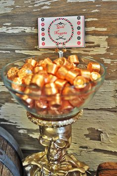 a glass bowl filled with candy sitting on top of a wooden table