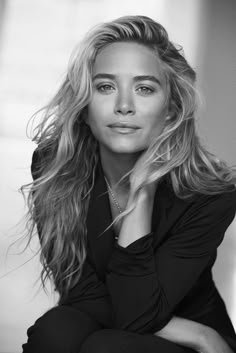 a black and white photo of a woman with long blonde hair wearing a shirt looking at the camera