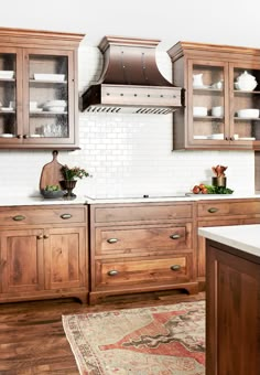 a kitchen with wooden cabinets and white tile backsplashes, an area rug on the floor