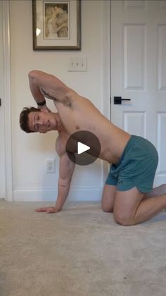 a man in blue shorts is doing a yoga pose on the floor with his hands behind his head