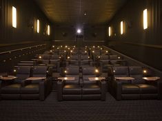 an empty movie theater with leather seats and candles lite up in the dark room