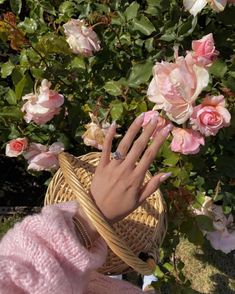 a woman's hand with pink manicures on her nails in front of flowers