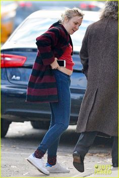 a woman is walking down the street with her hand in her pocket and another person behind her