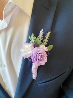 a boutonniere with purple flowers and greenery is worn on a man's lapel