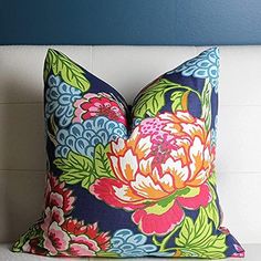 a colorful floral pillow sitting on top of a white couch next to a blue wall