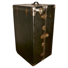 an old black suitcase with brass hardware on the front and sides is shown against a white background