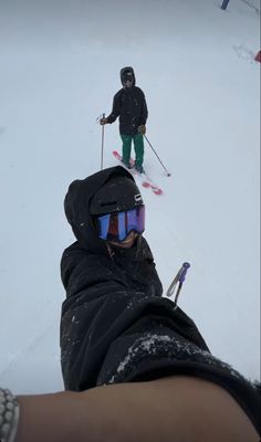 a person wearing skis and goggles standing in the snow with their feet up