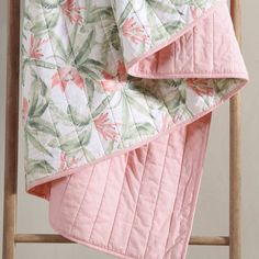 a pink quilted blanket on top of a wooden chair