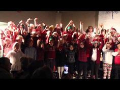 a group of children standing next to each other in front of a crowd with their hands up