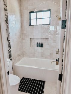 a bathroom with a bathtub, toilet and rug