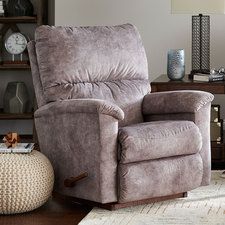 a living room with a chair, ottoman and clock on the wall behind it in front of a bookshelf