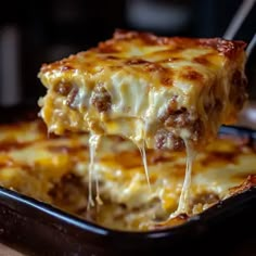 a piece of lasagna being lifted from a casserole dish with cheese