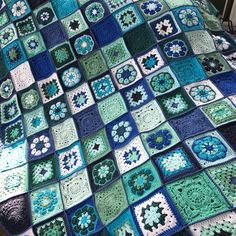 a crocheted blanket with blue, green and white squares