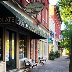 a row of benches sitting on the side of a street next to tall brick buildings