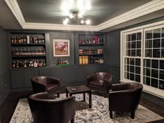 two leather chairs sitting in front of a bar with liquor bottles on the shelves behind them