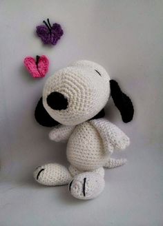 a crocheted stuffed dog sitting next to two butterflies