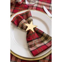 a red and gold plaid napkin with a star on it sits on a white plate