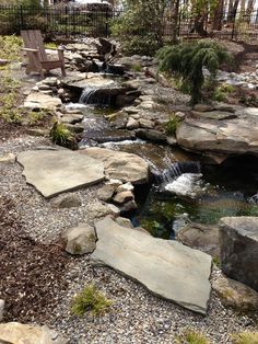 a garden with rocks, water and a bench