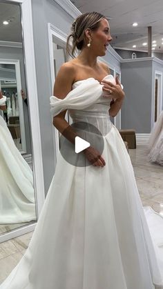 a woman in a wedding dress looking at herself in the mirror