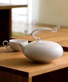 a white tea pot and two cups on a wooden table