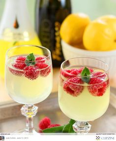 two glasses filled with lemonade and raspberries