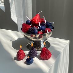 a bowl filled with berries and candles on top of a white tablecloth covered table