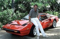 a man sitting on the hood of a red sports car