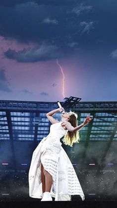 a woman in a white dress is performing on stage