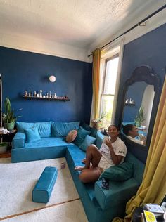 a man sitting on top of a blue couch in a living room