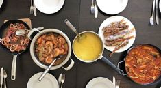 a table topped with plates and bowls filled with food next to silver utensils