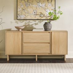 a wooden cabinet with two vases and a painting on the wall in the background