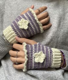 two hands wearing knitted gloves with hearts on them