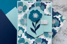 a close up of a card with blue flowers on it and the words hello written in white