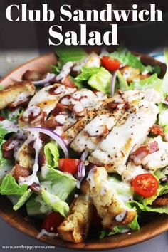 a salad with chicken, lettuce and tomatoes on it in a wooden bowl