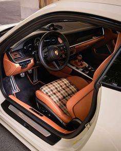 the interior of a white sports car with brown leather trims and plaid seat covers