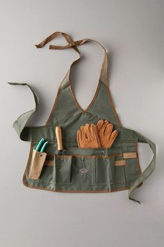 an apron with gardening tools hanging from it's back and two pairs of gloves in the pocket