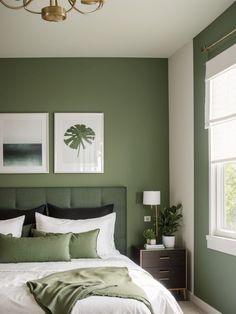 a bedroom with green walls and white bedding, two framed pictures on the wall