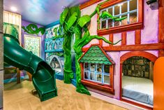 a child's playroom with a slide in the middle and a mural on the wall