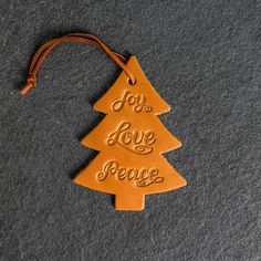 a leather ornament that says, you're love peace with a tree on it