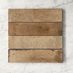 three different types of tile on a white counter top, one is brown and the other is beige