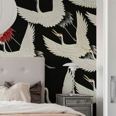 there is a bed with two white birds on the wall and a black background behind it