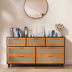 a wooden dresser sitting in front of a wall with a mirror on top of it