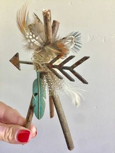 a hand holding an arrow made out of twigs and feathers