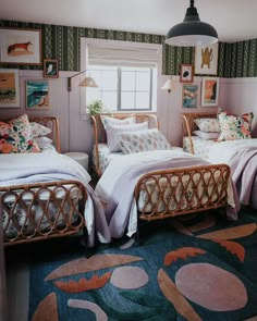 two twin beds in a room with pictures on the wall and rugs around them