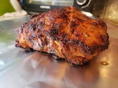 a piece of meat sitting on top of a metal counter next to a microwave oven