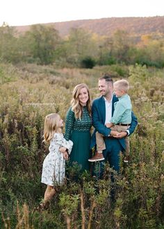 a family standing in the tall grass with their toddler son and mom looking at him