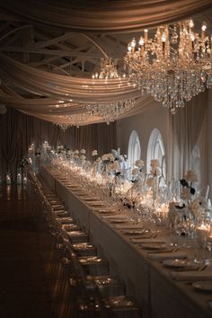 a long table is set with clear wine glasses and place settings for the guests to sit down