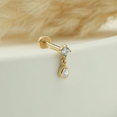 a gold earring with two white stones on it and a fur lined back ground