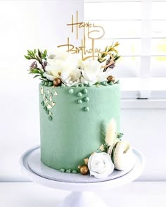 a birthday cake decorated with flowers and greenery